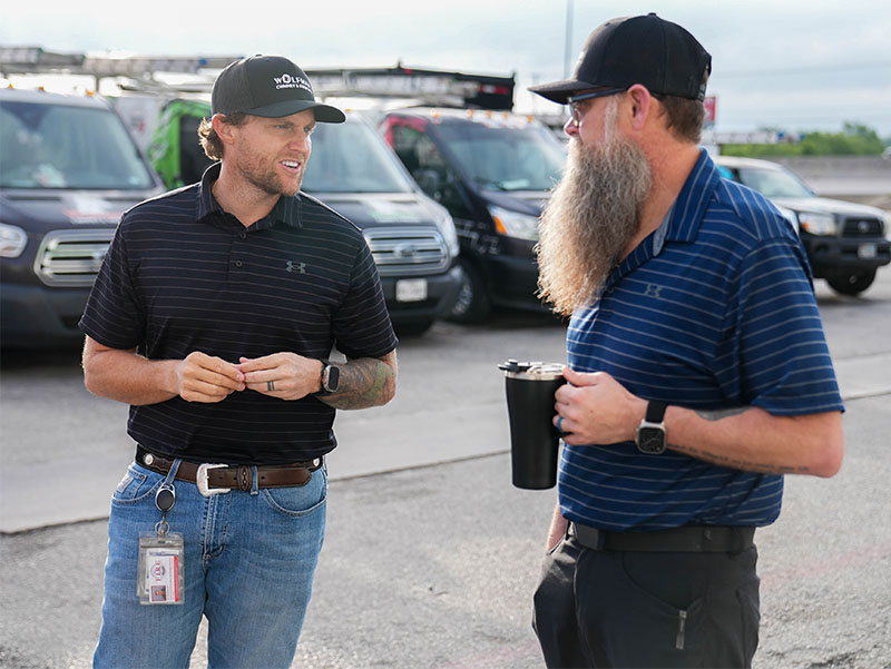 Owner and general manager talking in front of work vans.