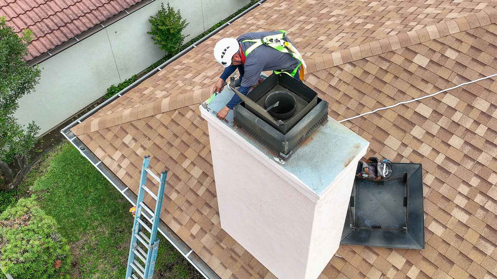 Chimney technician on the roof performing installation wearing harnesses and helmets.